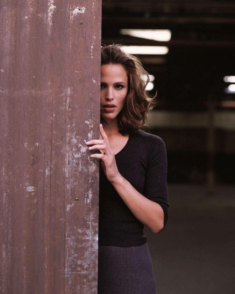 Jennifer Garner peeking behind rustic wall creating mysterious and intriguing wallpaper background