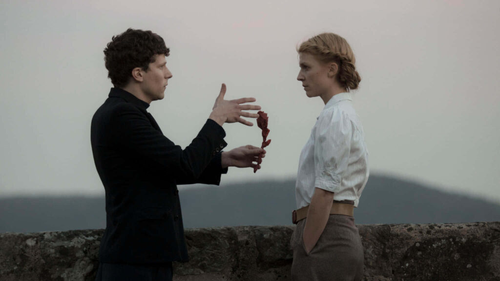 Jesse Eisenberg outdoors holding red object facing woman calm muted landscape wallpaper background