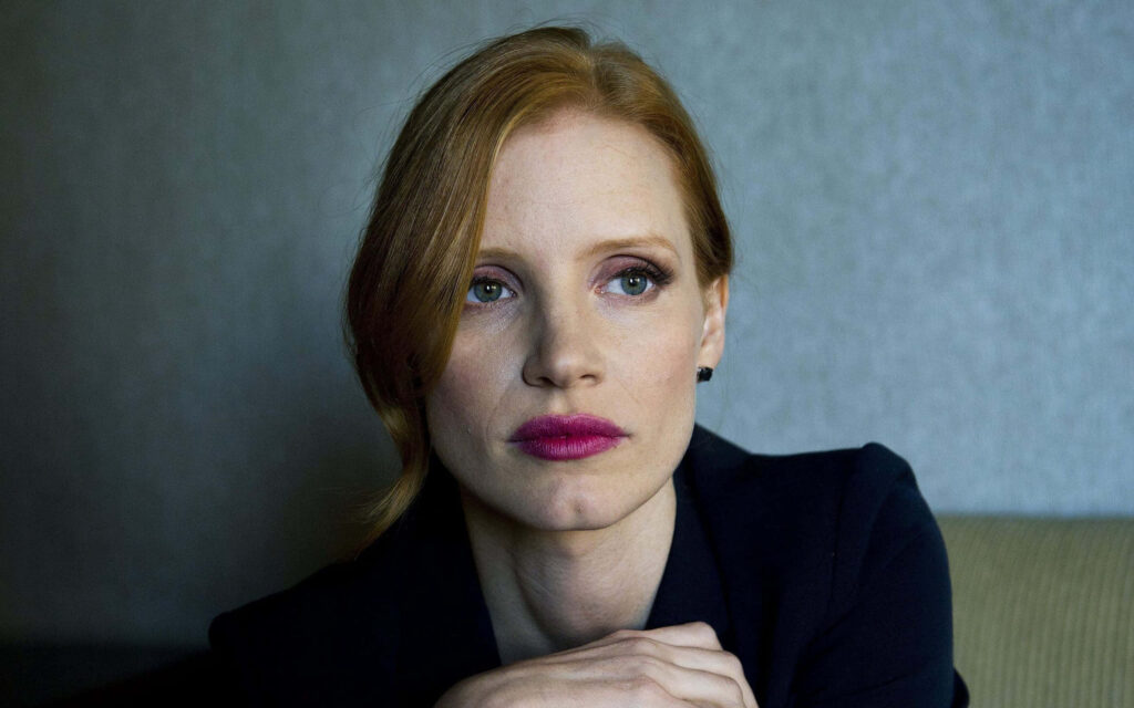 Jessica Chastain elegant wallpaper in stylish chic attire posing thoughtfully for background