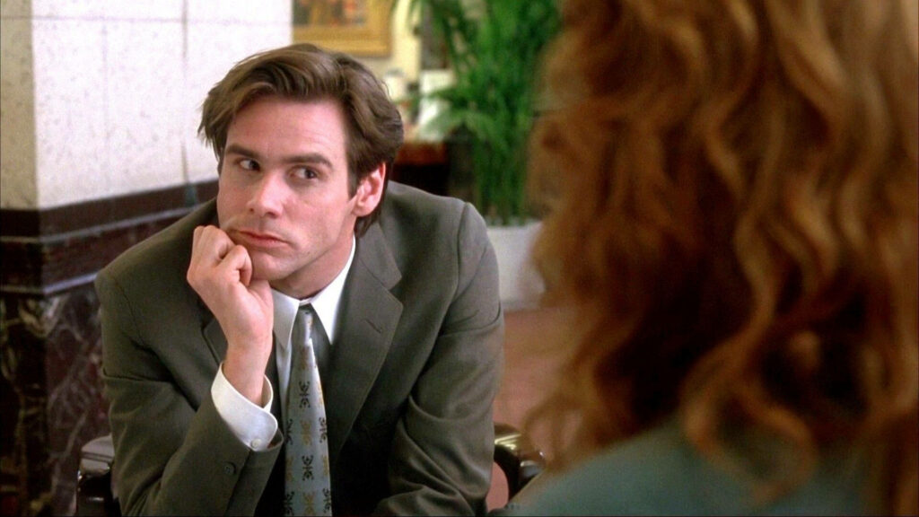 Jim Carrey hilarious stare in suit sitting with chin on hand comedic expression wallpaper