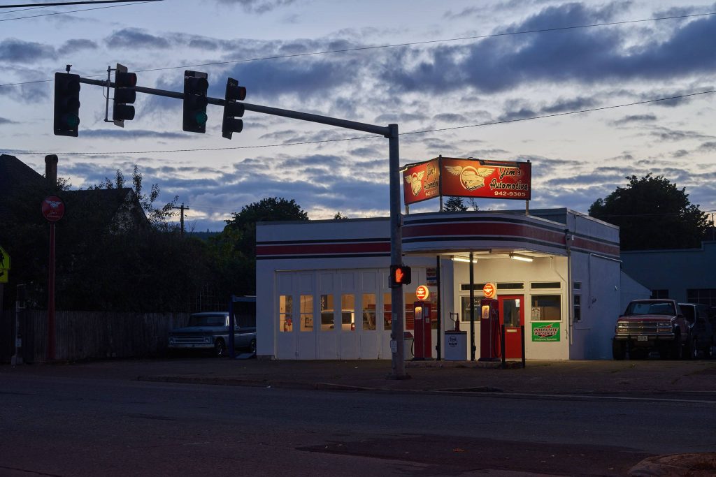 Retro gas pumps and classic pickup under stoplight twilight at Jim's Automotive wallpaper