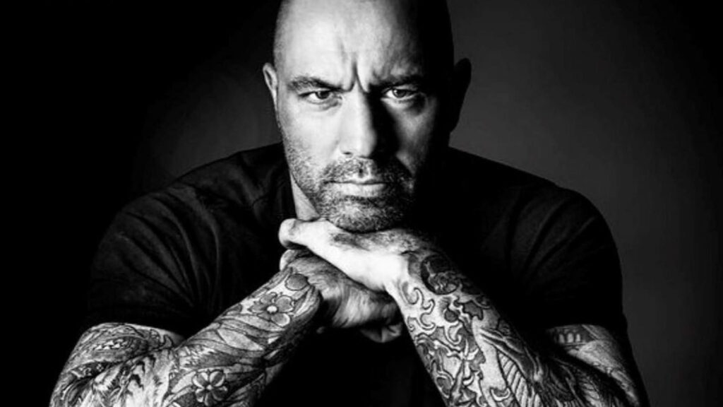 Black and white wallpaper of podcast host Joe Rogan with tattooed arms and serious expression