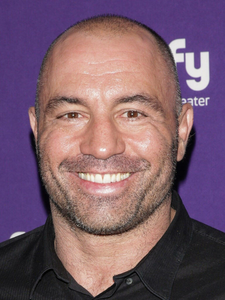Joe Rogan confident smile red carpet vibrant purple background podcast host wallpaper
