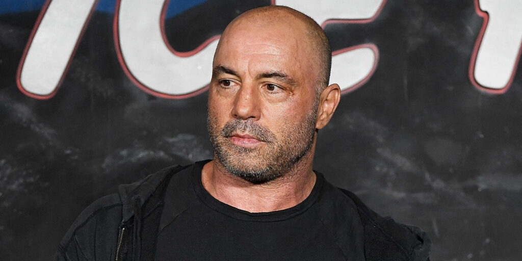 Joe Rogan engaged in public event showing intense focus and charismatic presence wallpaper background