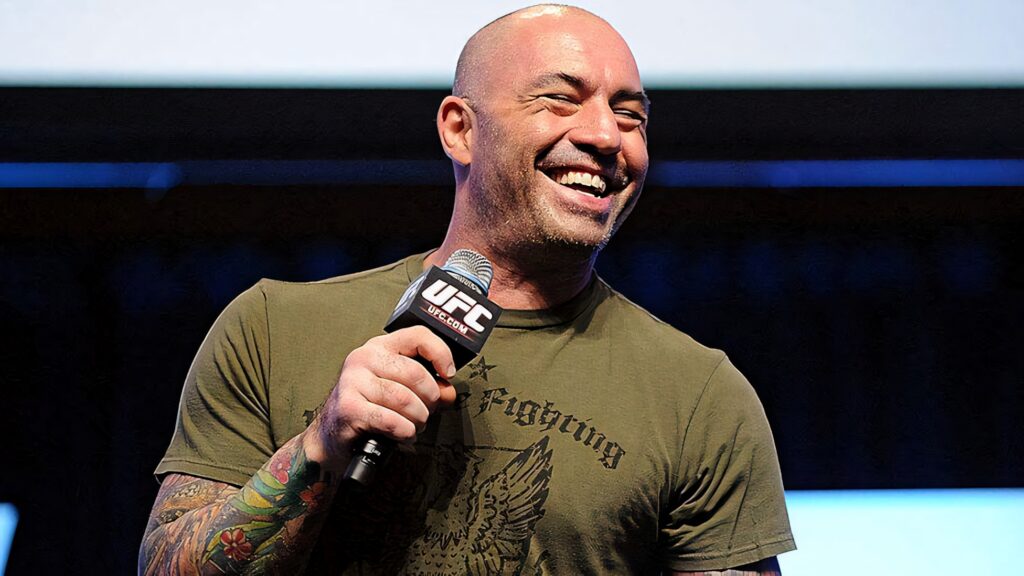 Joe Rogan smiling and holding microphone hosting UFC event showing energy and enthusiasm Wallpaper