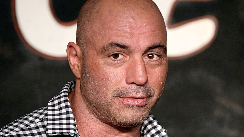 Joe Rogan smiling warmly with a blurred background in an engaging podcast wallpaper image