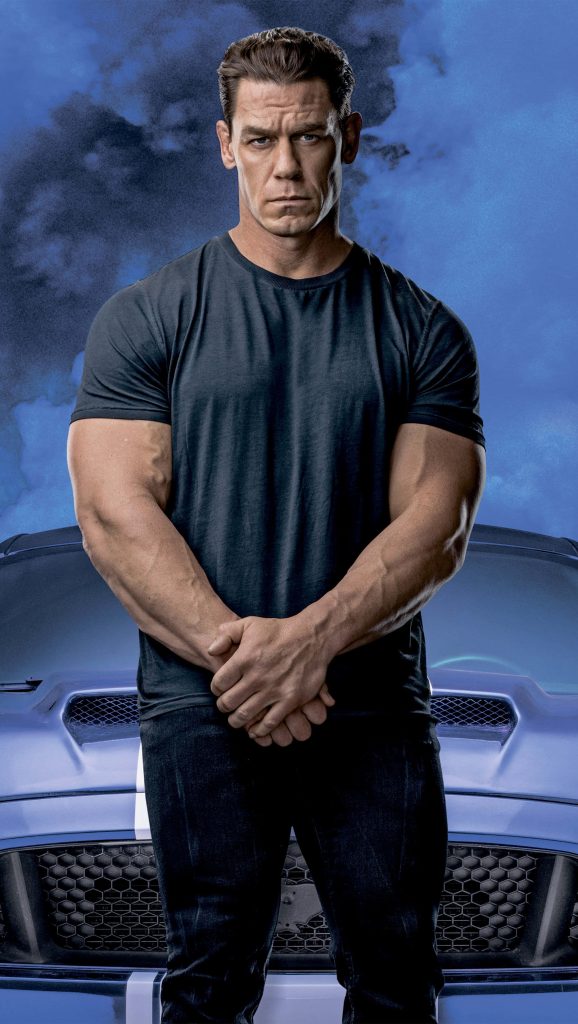 John Cena in black shirt standing confidently by blue muscle car with cinematic blue backdrop Wallpaper