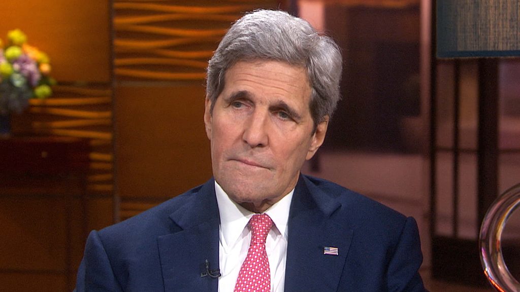 John Kerry in tailored suit and red tie during soft-lit studio interview on foreign policy Wallpaper