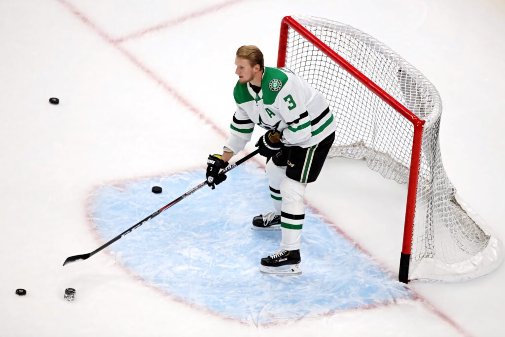 John Klingberg Dallas Stars practicing defensive hockey skills in green white uniform on ice rink Wallpaper