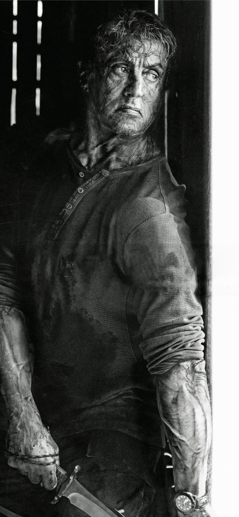 Black and white hyper-realistic Rambo Sylvester Stallone holding combat knife intense action wallpaper