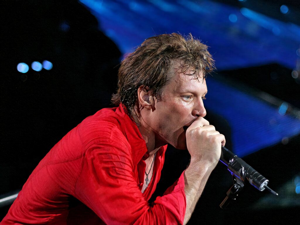 Jon Bon Jovi performing live at Madison Square Garden wearing red shirt vibrant concert lighting Wallpaper