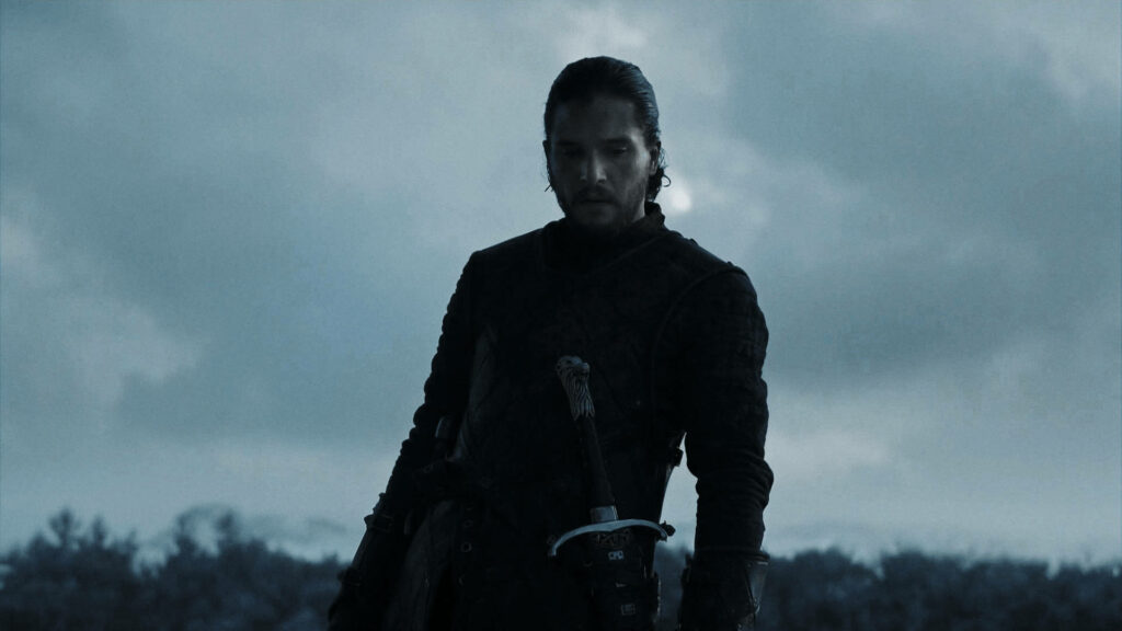 Jon Snow Dramatic Wallpaper: Intense Pose Against Cloudy Sky