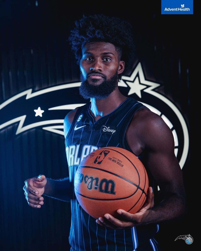 Jonathan Isaac Orlando Magic wallpaper in black pinstripe jersey holding basketball with blue glow