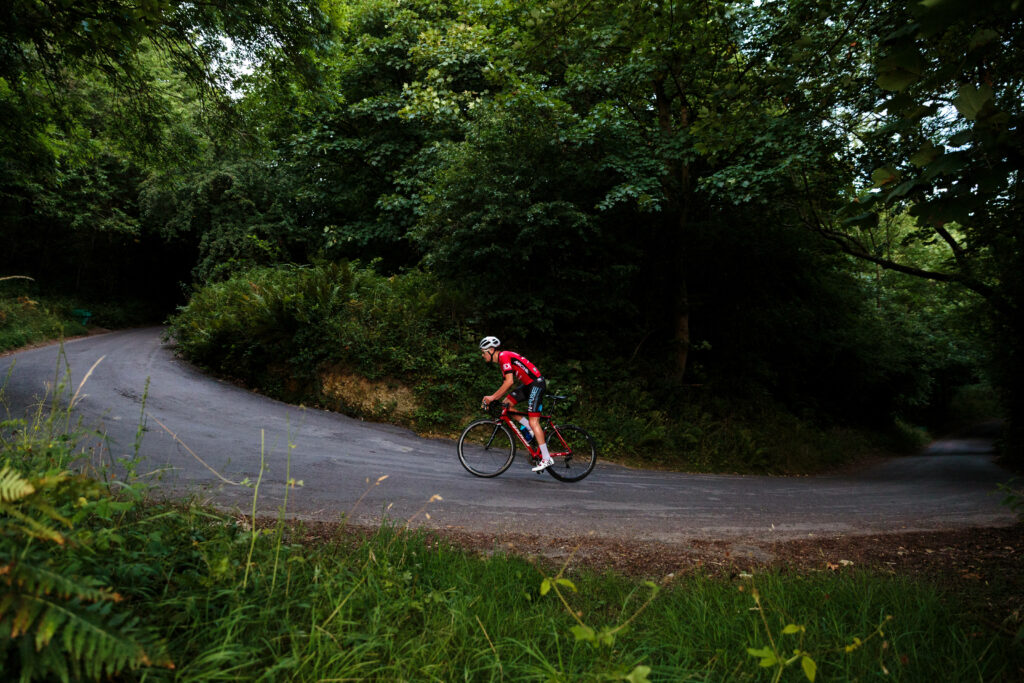 Thrilling Outdoor Adventure: Red Shirted Cyclist Conquering Serpentine Mountain Trails amidst Enchanting Greenery Wallpaper