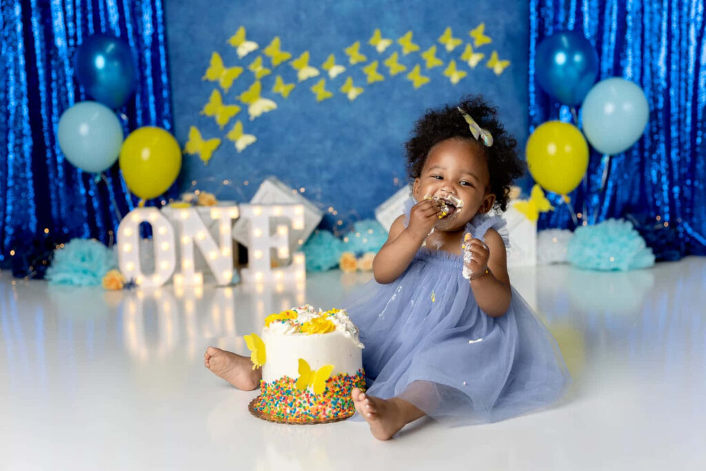 Joyful Baby Girl's First Birthday Cake Smash in Cute Blue Dress Wallpaper