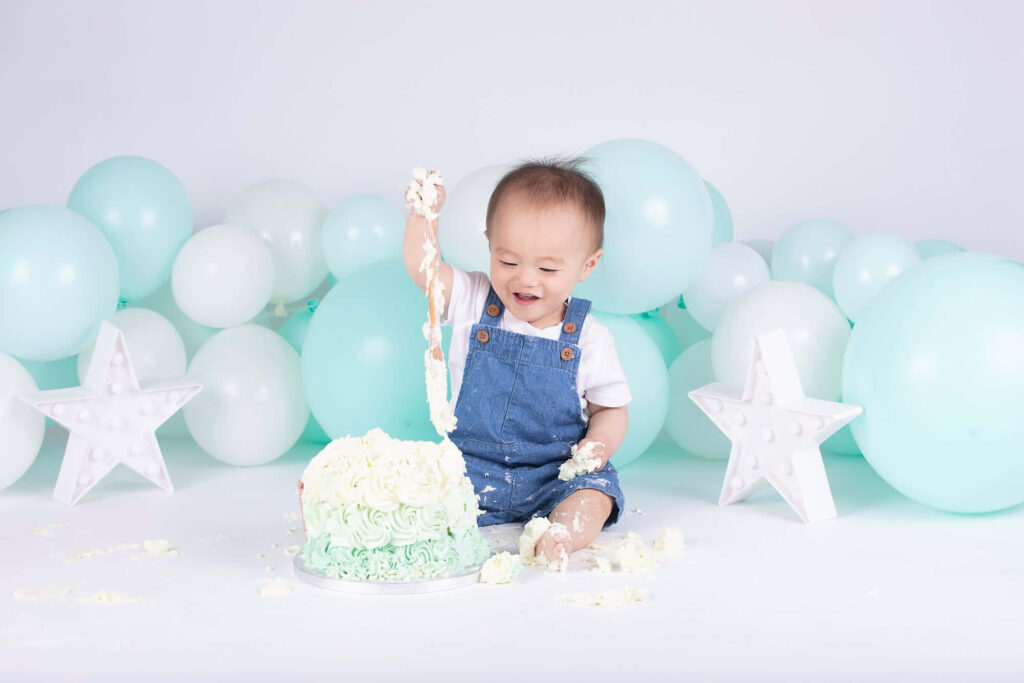 Joyful Baby Enjoys Pastel Cake Surrounded by Balloons and Stars Wallpaper