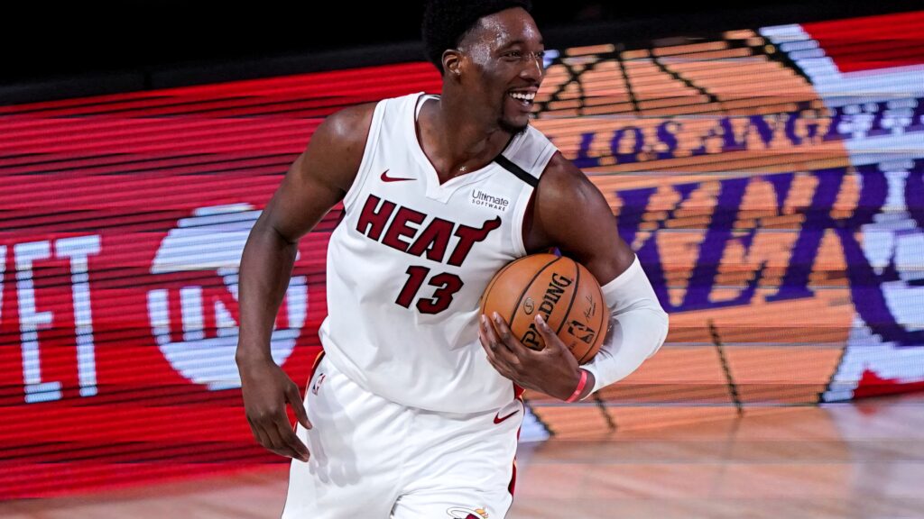 Bam Adebayo smiling in Miami Heat jersey holding basketball on court basketball wallpaper background