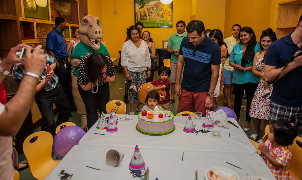 Joyful Birthday Celebration: Laughter, Cake & Dino Costume Fun! Wallpaper
