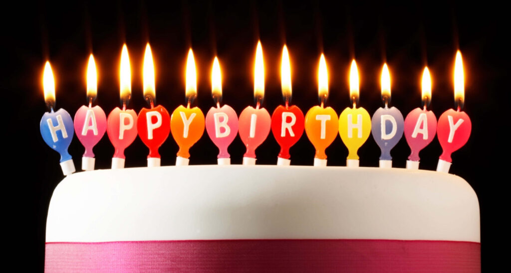 Colorful Birthday Candles on Cake with Bright Pink Ribbon Wallpaper