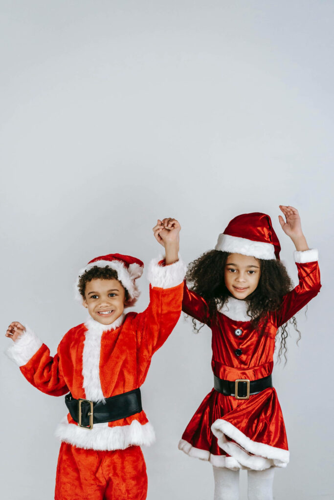 Joyful Kids in Santa Outfits: Festive Holiday Wallpaper for Cheer