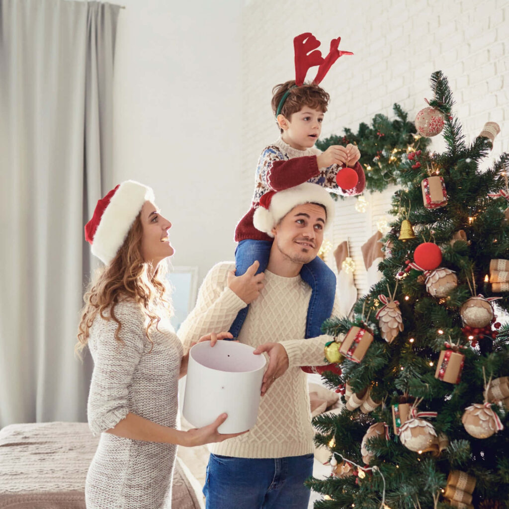 Joyful Family Decorates Christmas Tree in Cozy Holiday Setting Wallpaper