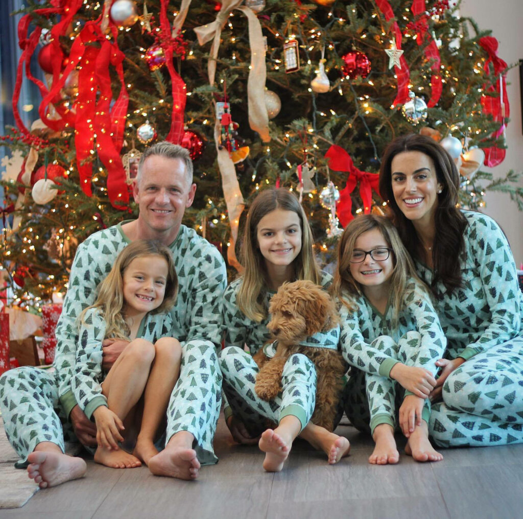 Joyful Family in Matching Pajamas by Festive Christmas Tree Wallpaper