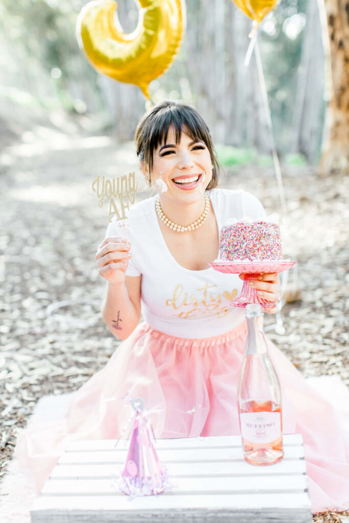 Joyful Forest Celebration: Smiling Woman with Cake & Gold Balloons Wallpaper