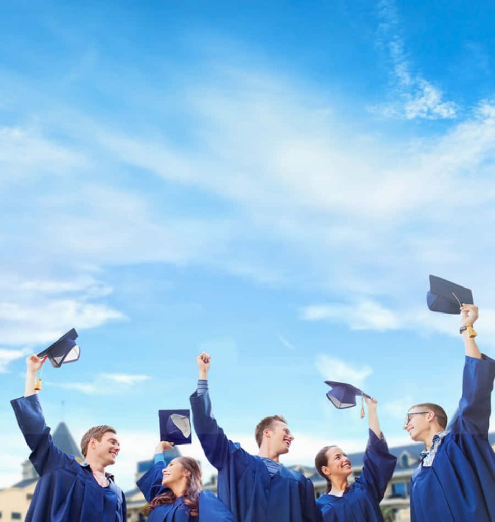 Joyful graduates in blue gowns tossing caps with clear sky celebrating academic success Wallpaper