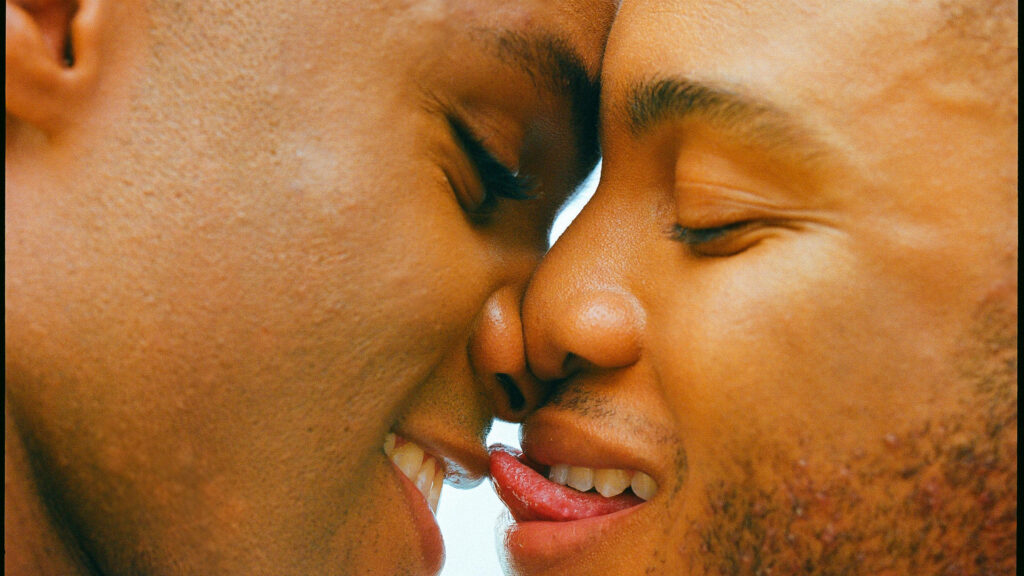 Close up of two Black men sharing joyful intimate moment with bright natural light background Wallpaper