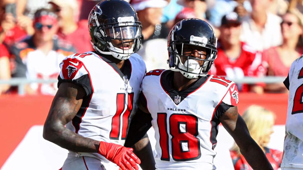 Julio Jones and Calvin Ridley in Atlanta Falcons uniforms standing together on sunlit football field Wallpaper
