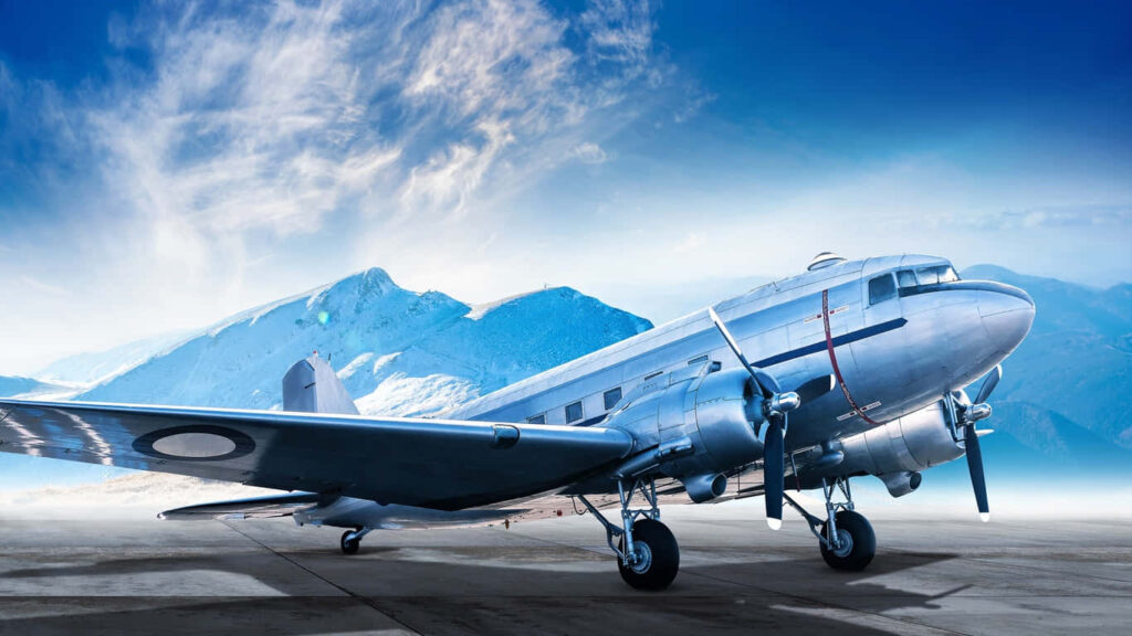 Frozen Beauty: A Majestic Douglas DC-3 Amidst Mountainous Grandeur Wallpaper