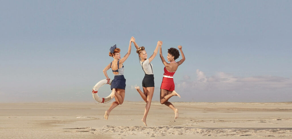 Jumping for Joy: A Beach Day with 90's Women Friends Wallpaper
