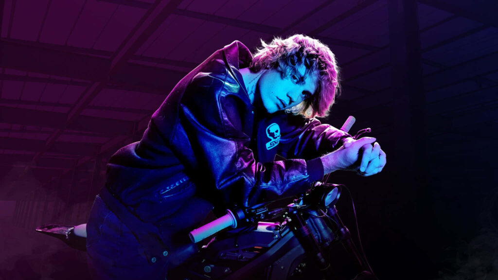 Justin Bieber leaning on motorcycle with purple blue lighting reflecting change and anticipation wallpaper
