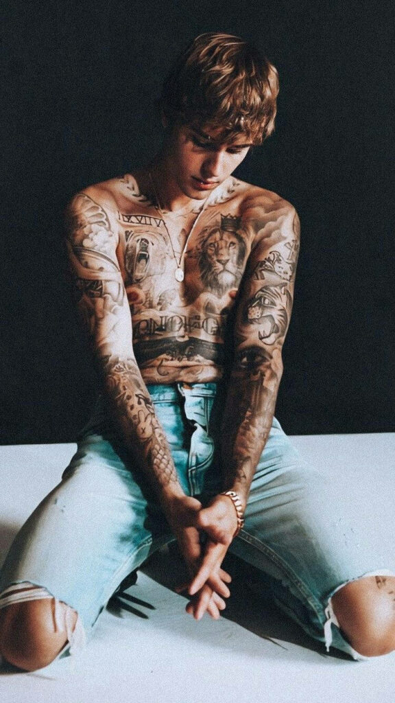 Justin Bieber shirtless showcasing detailed tattoos wearing ripped jeans bold stylish wallpaper