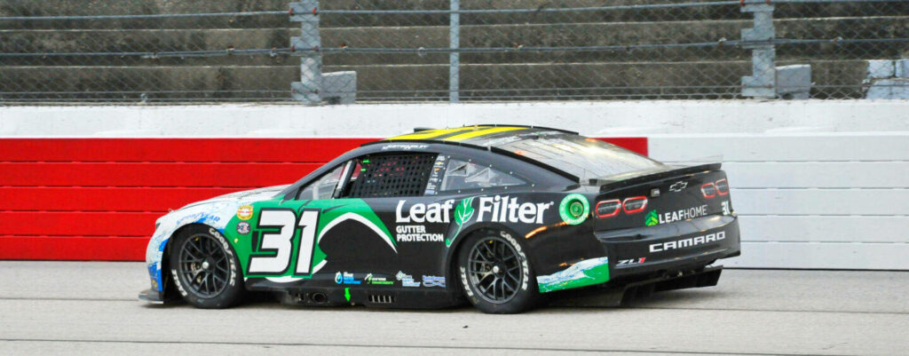 Justin Haley black green Camaro race car with Leaf Filter sponsor speeding on track wallpaper