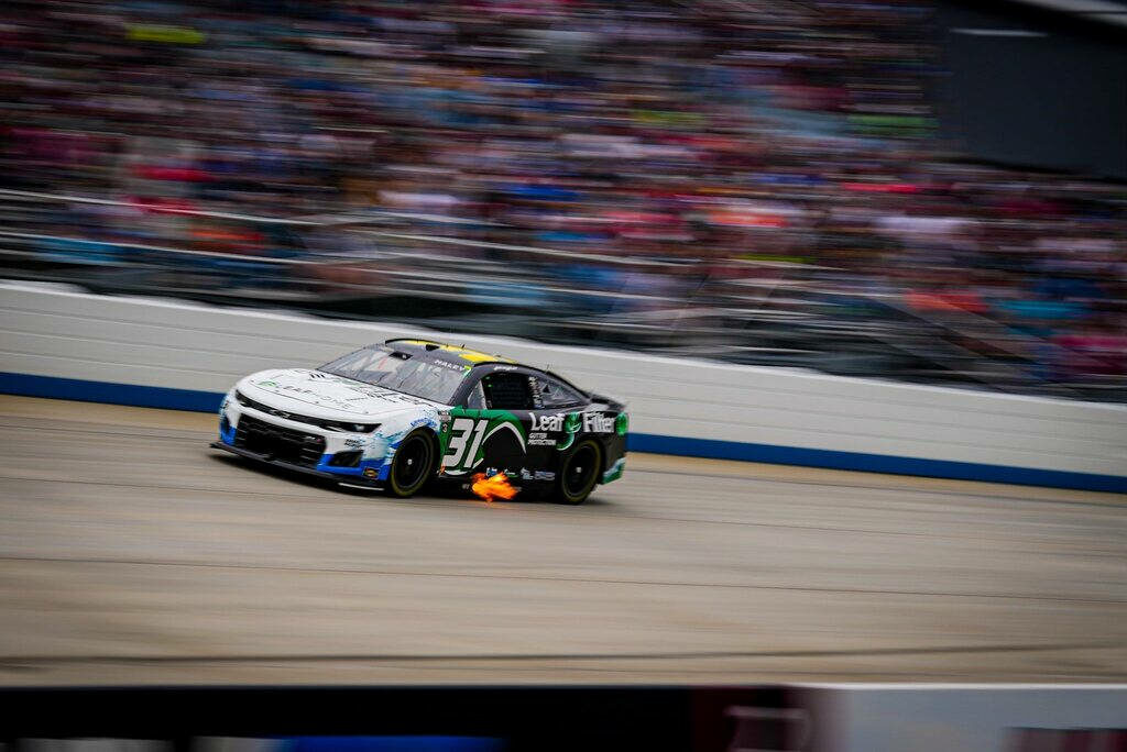 Justin Haley races number 31 car with flames from exhaust and blurred crowd at high-speed race Wallpaper