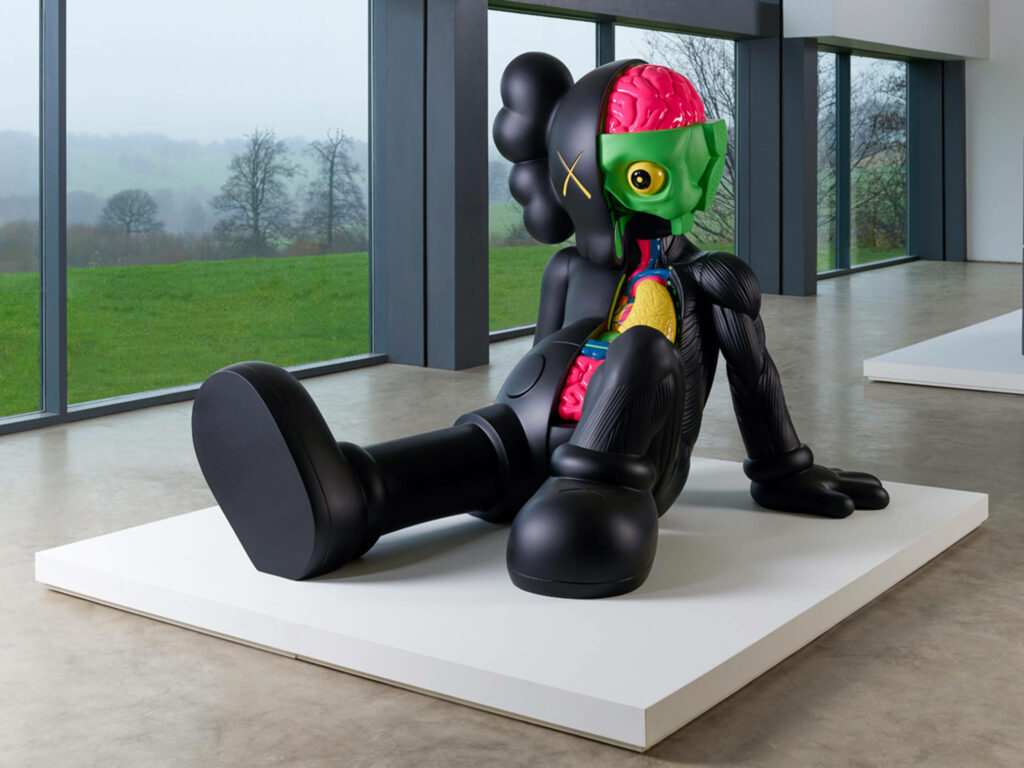 KAWS Dissected Sculpture black figure with vibrant anatomy in modern gallery with green view wallpaper
