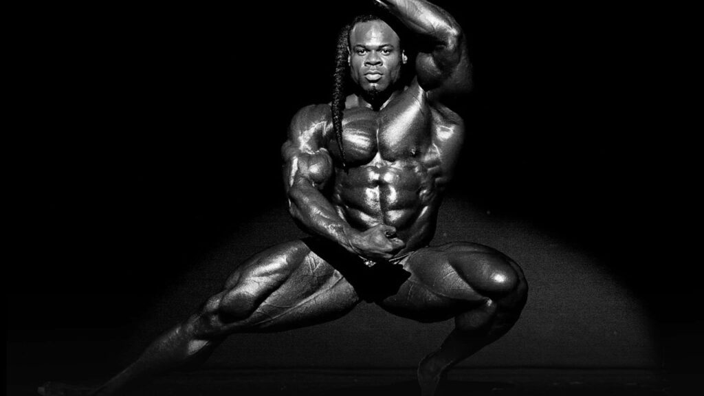 Kai Greene muscular bodybuilding pose dramatic lighting dark background wallpaper background