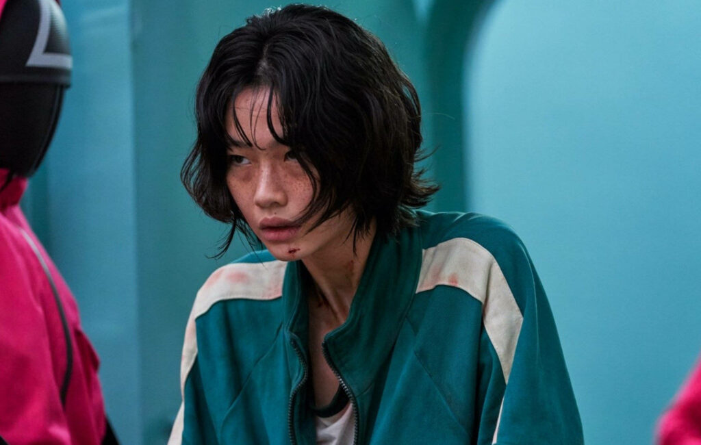 The Resilient Contestant: Kang Sae-byeok Faces the Menacing Guard in Squid Game Wallpaper