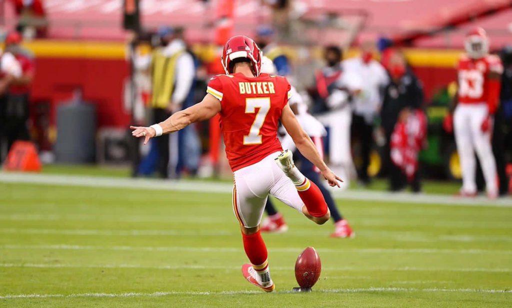Kansas City Chiefs kicker Harrison Butker number 7 kicking field goal vibrant stadium lights wallpaper