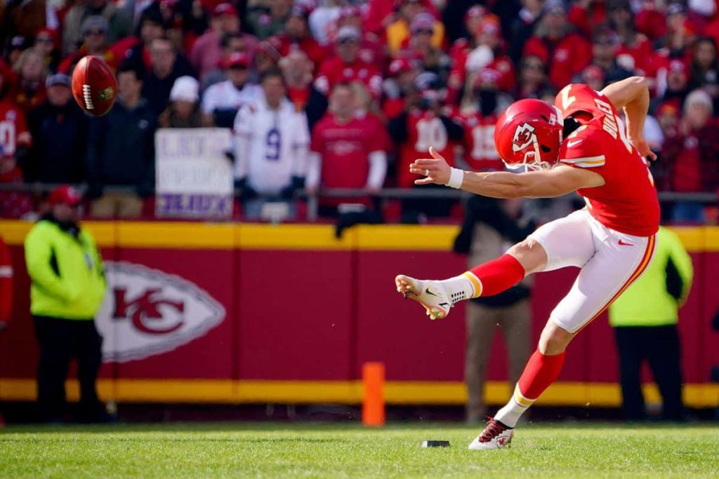 Kansas City Chiefs kicker Harrison Butker mid-kick in red white uniform NFL action wallpaper