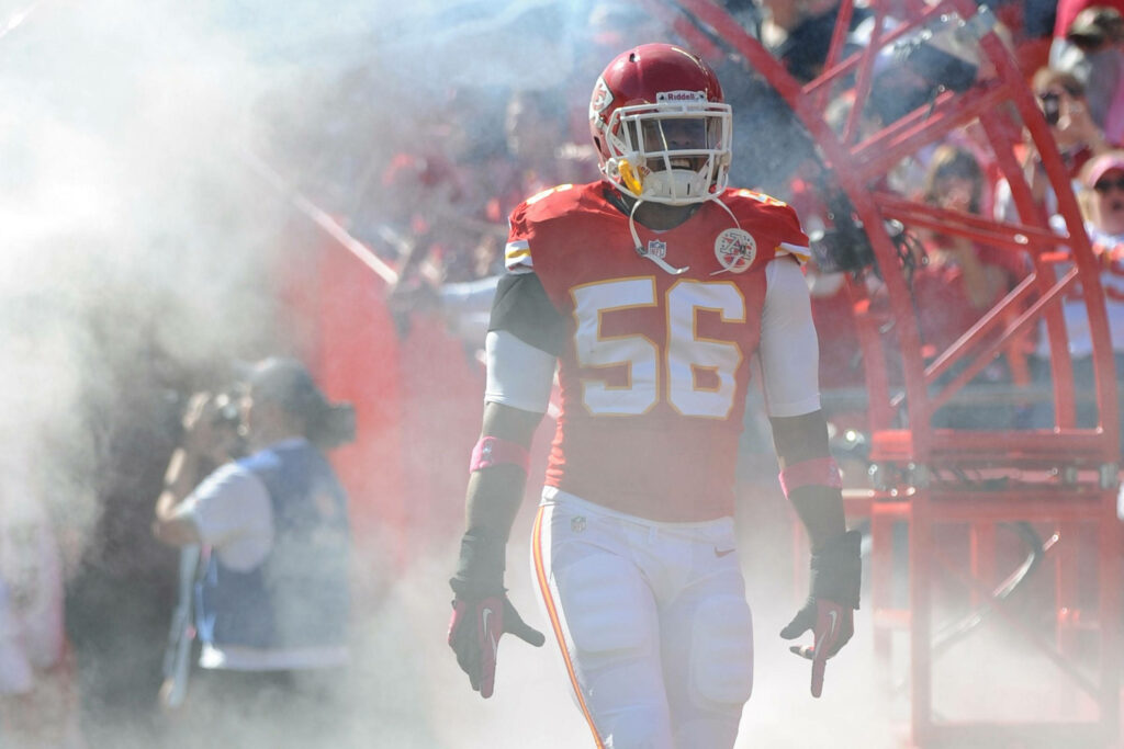 Kansas City Chiefs player number 56 stands confidently on field emerging through smoke wallpaper