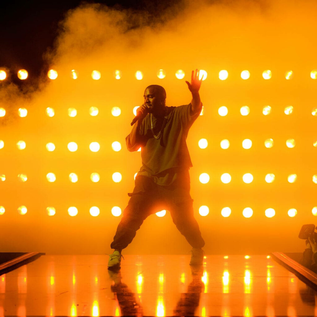 Kanye West Saint Pablo Era: Iconic Performance with Golden Stage Lights Wallpaper
