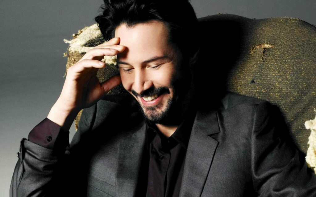 Warm Candid Keanu Reeves Wallpaper in Stylish Dark Suit