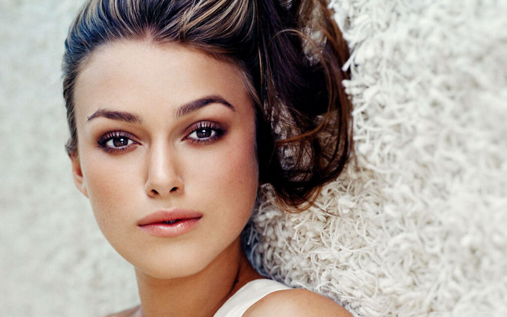 Close-up of Keira Knightley's expressive eyes and soft features on textured neutral wallpaper background