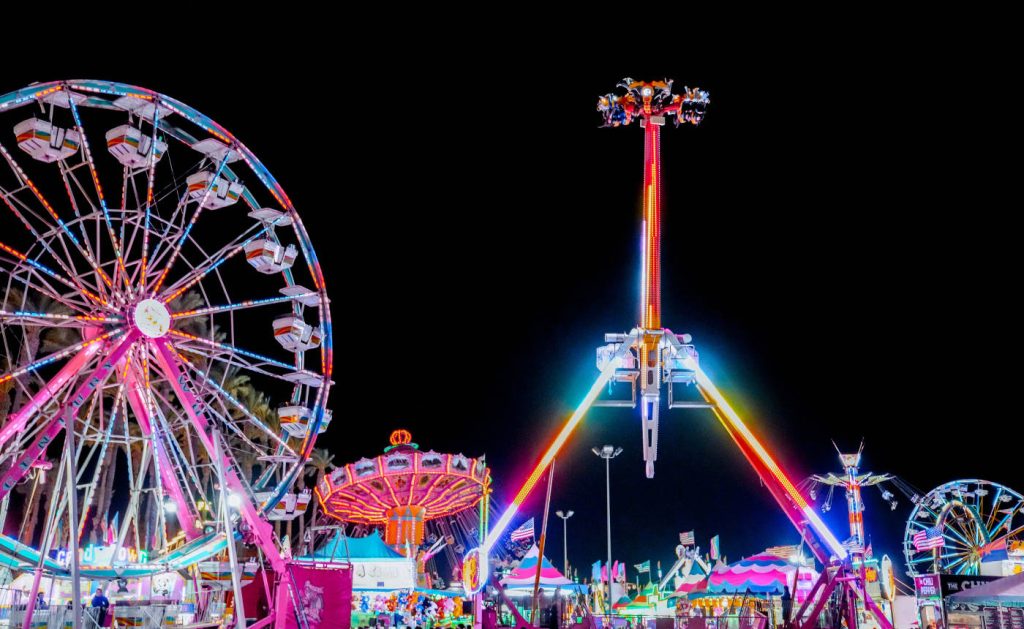 Kern County Fair night scene with glowing Ferris wheel and neon pendulum ride vibrant carnival Wallpaper