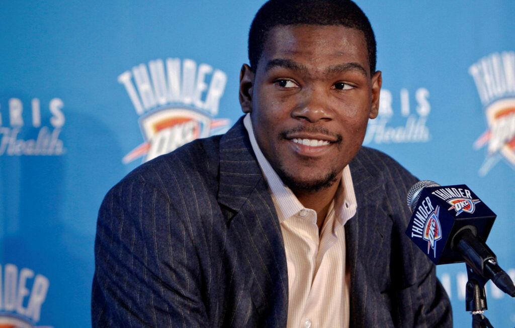 Kevin Durant Smiling at Press Conference with Thunder Logo Wallpaper