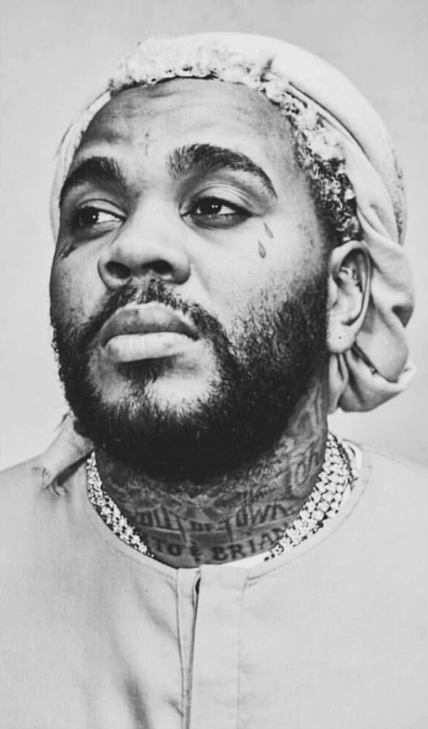 Monochrome portrait of rapper Kevin Gates with facial tattoos and iced-out chain wallpaper