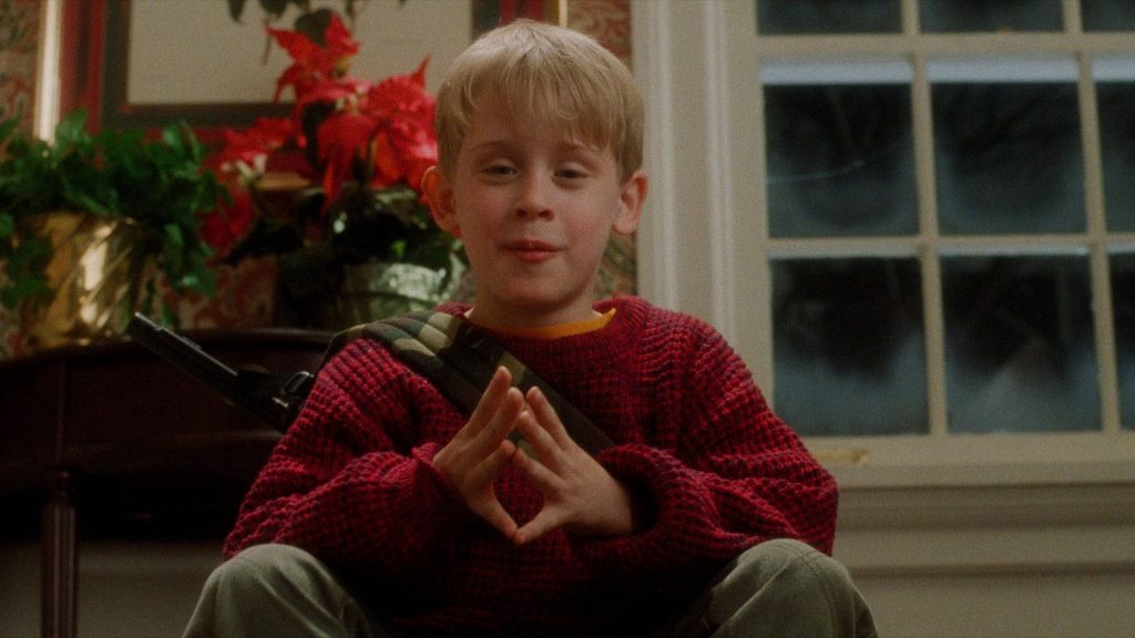 Macaulay Culkin as Kevin McCallister in iconic Home Alone red sweater plotting indoors wallpaper