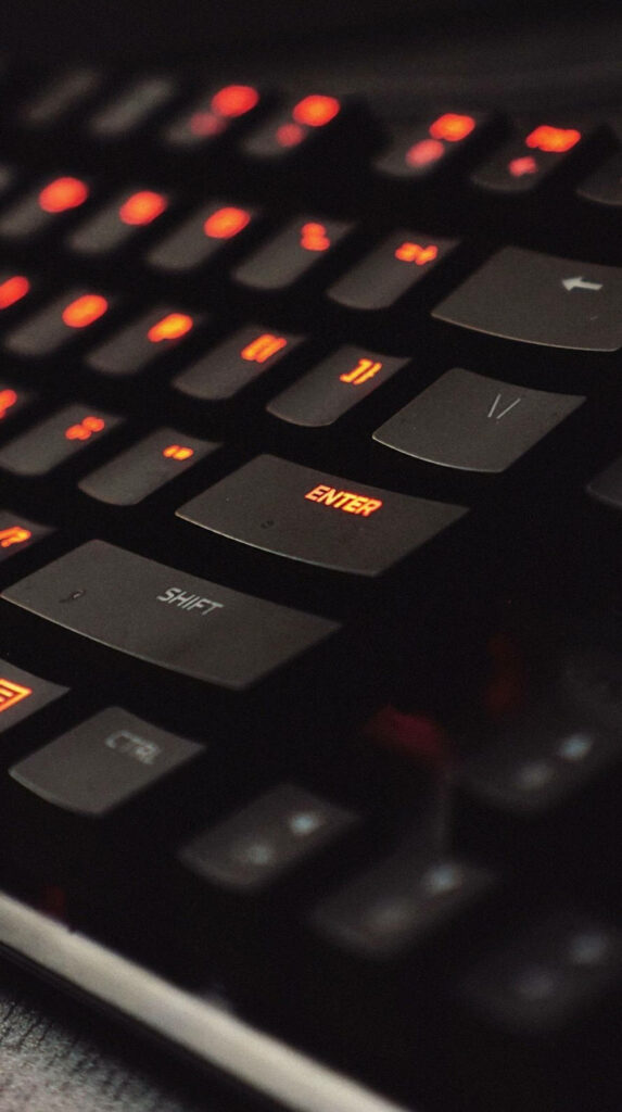Immersive Gaming Experience: Vibrant Orange Key Lighting on Sleek Black Keyboard Wallpaper
